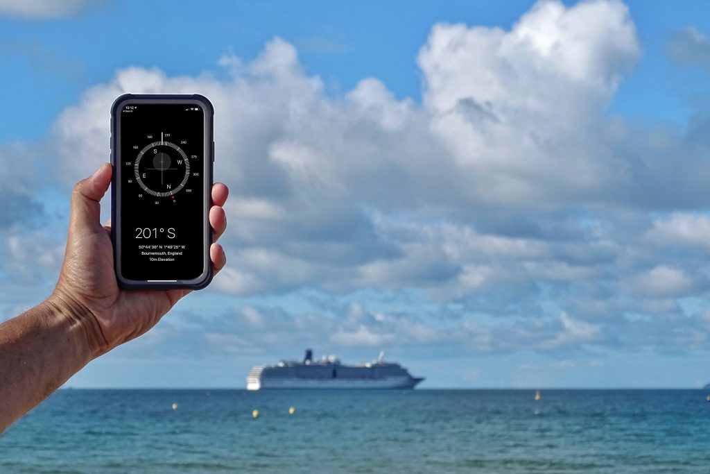 Hand hält Smartphone im Hintergrund Kreuzfahrtschiff